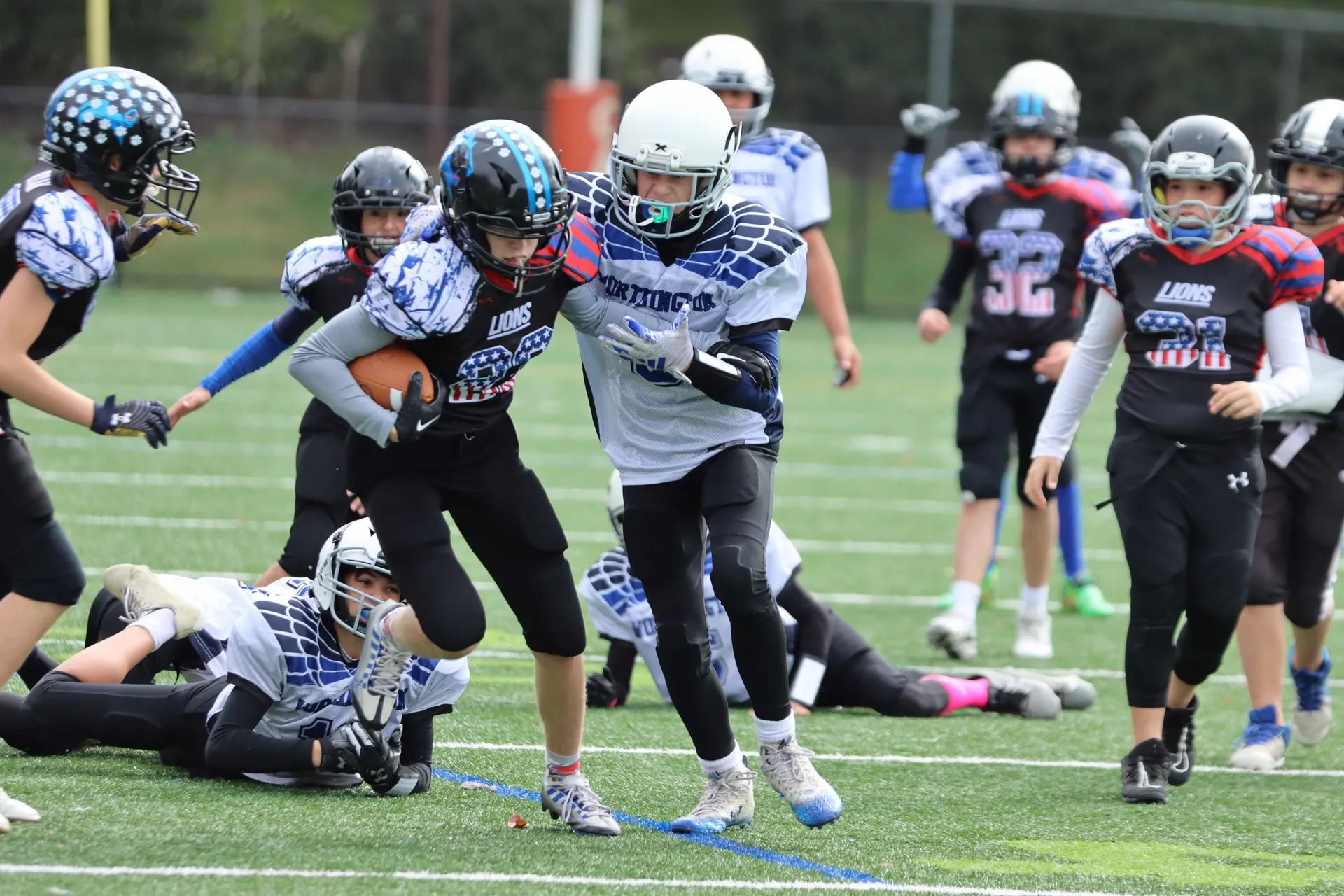 A Lions ball carrier breaks through a tackle on an overcast afternoon.
